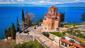 an old church on a hill next to the water at White Blue Ohrid - Free Parking Balcony near Lake and Old Town Apartments in Ohrid