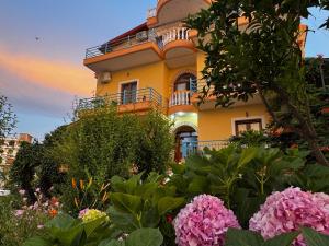 a yellow building with a lot of flowers in front of it at Vila Laura in Ksamil
