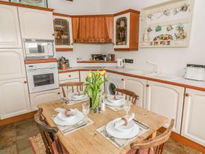 a kitchen with a wooden table and chairs in a kitchen at The Bothy in Leyburn
