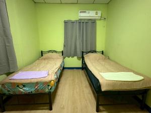 two beds in a room with green walls at Worsakornrit Homestay in Bangkok