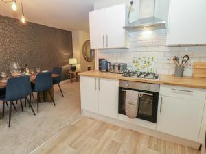 a kitchen with white cabinets and a dining room with a table at Eleven Tides in Seaham