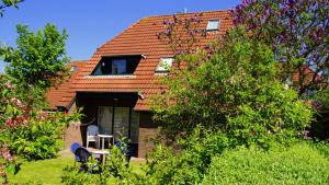 a house with two chairs and a window and trees at Nordseewohnung Strandloeper in Wittmund