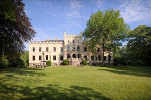 a large white house with a large grass yard at Romantik Hotel Schloss Reichenow in Reichenow