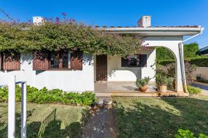 a white house with an arch and some plants at Casa da Torreira in Torreira
