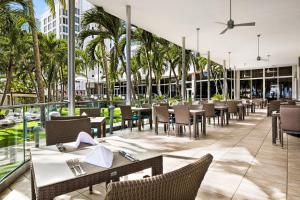 a restaurant with tables and chairs and palm trees at Riu Plaza Miami Beach in Miami Beach
