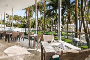 a restaurant with tables and chairs and palm trees at Riu Plaza Miami Beach in Miami Beach