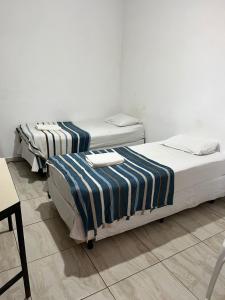 two beds in a room with a table and chairs at Hotel Araçariguama in Araçariguama