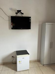 a flat screen tv on a wall next to a refrigerator at Hotel Araçariguama in Araçariguama
