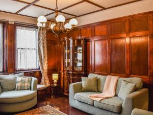 a living room with wooden walls and two couches and a chandelier at Heritage Lodge in Rhyl
