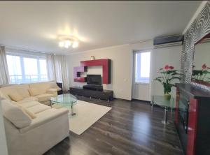 a living room with a white couch and a tv at M.Dosoftei 126 in Chişinău