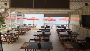 a restaurant with tables and chairs and red umbrellas at Pousada Amendoeira in Mangaratiba