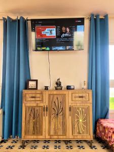 a tv on a wall with blue curtains at Maison de la Lagune in Oualidia +52 photos