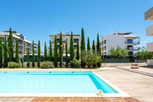 a swimming pool in a apartment with trees and buildings at Santa Maria Apartamentos in Tavira