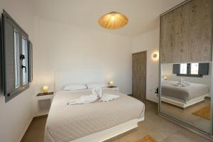 a white bedroom with a bed and a mirror at Aerial Apartments in Karterados