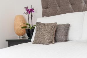 a white bed with two pillows and a plant on a table at Gilmour's Entry Apartment in Edinburgh