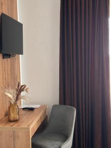 a room with a chair and a desk with a television at Hotel Fortuna in Gradačac
