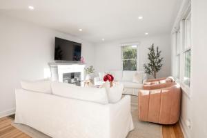a living room with white furniture and a fireplace at Renovated Cape Near Beach with Fire Pit in Fairfield