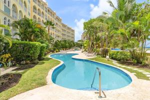 a pool at the resort with palm trees and a building at 101 Sapphire Beach Barbados in Christ Church