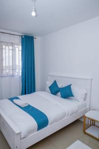 a white bed with blue pillows in a room at Chesum's suites in Eldoret
