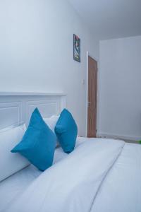 a white bed with two blue pillows on it at Chesum's suites in Eldoret +3 photos