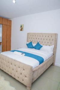 a bedroom with a large bed with blue pillows at Chesum's suites in Eldoret