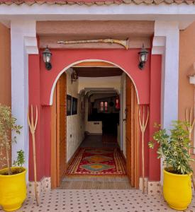 an entrance to a building with an arch and plants at Riad lina in Tafraout