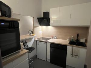 a small kitchen with white cabinets and a television at Loft 130m2 10pers idéal groupe famille in Marseille