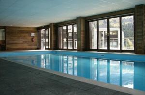 a large swimming pool in a building with windows at Pied des pistes, piscine, jacuzzi in Flaine