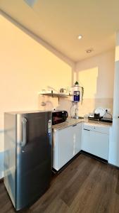 a kitchen with a black refrigerator and white cabinets at Sundowner Hive115 Jacuzzi studio Large grdan patio in Gurgaon