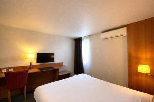a hotel room with a bed and a desk with a television at Kyriad Montargis Amilly in Amilly