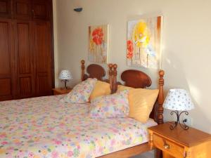 een slaapkamer met een bed en 2 lampen en schilderijen bij El Varadero in Igueste