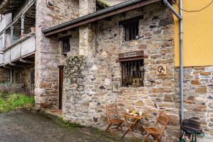 a table and chairs sitting outside of a stone building at La Casina Del Fornu in Pravia