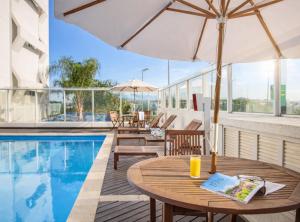 a table with an umbrella next to a swimming pool at Intercity Florianopolis in Florianópolis