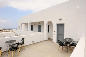 a balcony with black chairs and tables on a white building at Aerial Apartments in Karterados