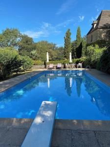 a swimming pool with blue water in a yard at La Maison du Gardien in La Celle-sous-Gouzon