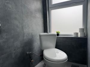 a bathroom with a white toilet and a window at E - Central Room Five in Skopje