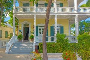 a yellow house with a white porch and stairs at Silver Palms Inn & Historic Homes in Key West