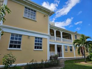 an exterior view of a yellow house with a palm tree at Modern 1 Bedroom Apartment Near Roseau in Canefield