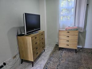 a television on top of a wooden dresser with a window at Modern 1 Bedroom Apartment Near Roseau in Canefield