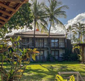 a house with palm trees in front of it at Aquarela Praia Hotel in Arraial d'Ajuda