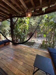 a hammock on a wooden deck with a tree at Green oasis across from the main street in Mazunte
