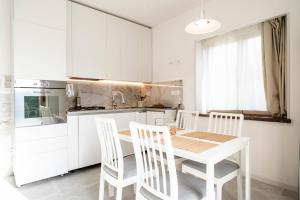a white kitchen with a wooden table and chairs at Al Melograno in Aquilinia