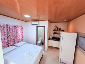 a bedroom with a white bed and a refrigerator at Flat Studio Casal - Praia da Lagoa do P a u - Coruripe in Coruripe