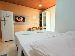a bedroom with a white bed and a refrigerator at Flat Studio Casal - Praia da Lagoa do P a u - Coruripe in Coruripe