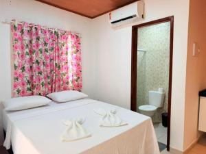 a bedroom with a white bed with a pink curtain at Flat Studio Casal - Praia da Lagoa do P a u - Coruripe in Coruripe
