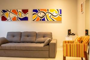a living room with a couch and paintings on the wall at Book Santos Mar à Vista no Unique Residence 1810 in Santos +37 photos