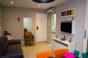 a living room with a couch and a tv on a wall at Book Santos Mar à Vista no Unique Residence 1810 in Santos
