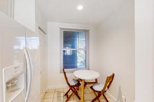 a kitchen with a table and two chairs and a refrigerator at Beautiful Oceanfront Getaway w/Shared Pool, Central AC, Elevator, & W/D in Fernandina Beach