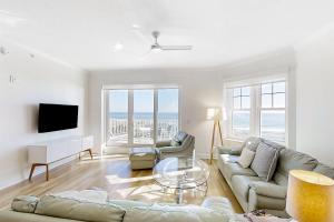 a living room with a couch and a tv at Beautiful Oceanfront Getaway w/Shared Pool, Central AC, Elevator, & W/D in Fernandina Beach