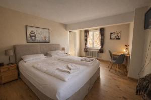 a bedroom with a large white bed and a desk at Pension Bergseeblick in Titisee-Neustadt